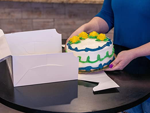 woman putting a decorated cake into a bakery box