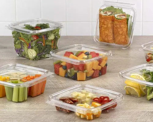 Clear plastic containers with various food items on a commercial kitchen counter